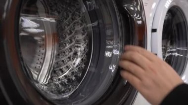 Çamaşır makinesinin kapısını aç. Müşteri, Ev Aletleri Mağazasında Yeni Çamaşır Makinesini Denetliyor