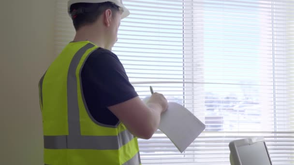 Un trabajador con casco lleva registros. Un capataz escribe en un diario. Ingeniero de Construcción Masculino Con Proyecto de Construcción en Papel, Hombre en Ropa Formal y Casco Controla el Trabajo — Vídeos de Stock