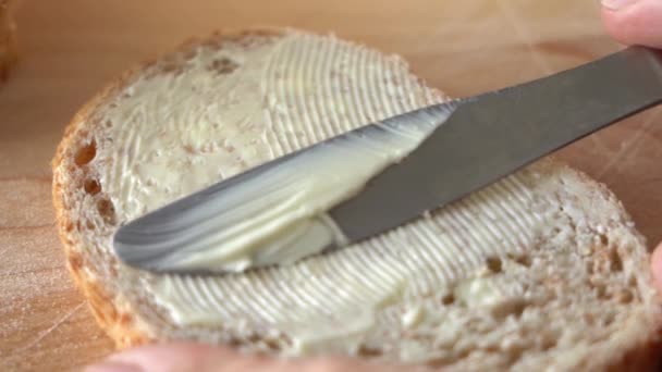 Šířit máslo na chléb. Pomalý nůž roztírající máslo po povrchu chleba. Detailní záběr — Stock video