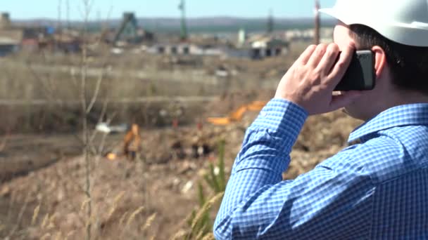 Um homem em um capacete de trabalho inspeciona um canteiro de obras — Vídeo de Stock