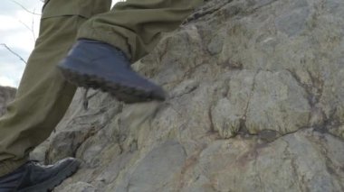 Dağlarda bir Yürüyüş Ayakları 'nın yakın çekimi, Taşın Üzerinde Bir Tekme. Dağ keşfi macerasındaki yürüyüş botları içindeki adam.