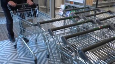 Alışveriş yapan bir erkeğin eli süpermarkette ya da markette boş bir market arabasını dizerken yakın plan çekilmiş.