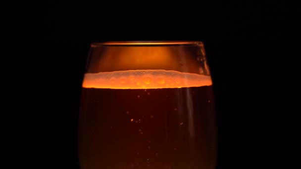 Склянка наповнена легким пивом. Світле пиво в склянку на темному тлі — стокове відео