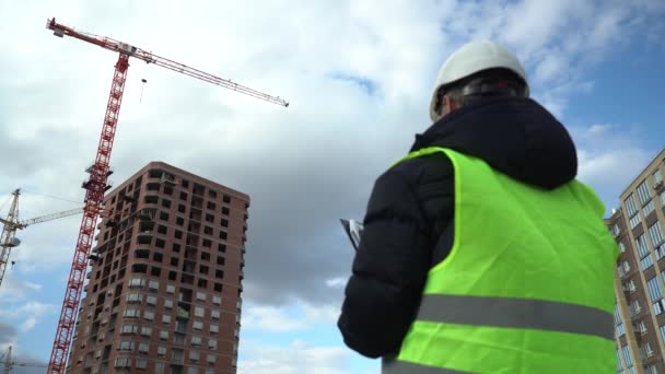 Konsultingenjör på byggarbetsplatsen som håller ritningen i handen. Bygginspektör. Ritning över byggarbetsplatsen och arbetsflöde för nya byggnader — Stockvideo