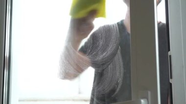Bir adam pencereyi bez parçasıyla yıkıyor. Ev işi, temizlik..