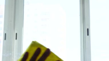 Bir adam pencereyi bez parçasıyla yıkıyor. Ev işi, temizlik..