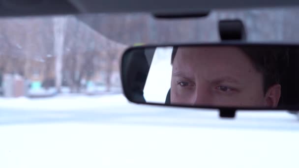 Очі молодого чоловіка відображаються у дзеркалі автомобіля. Крупним планом — стокове відео