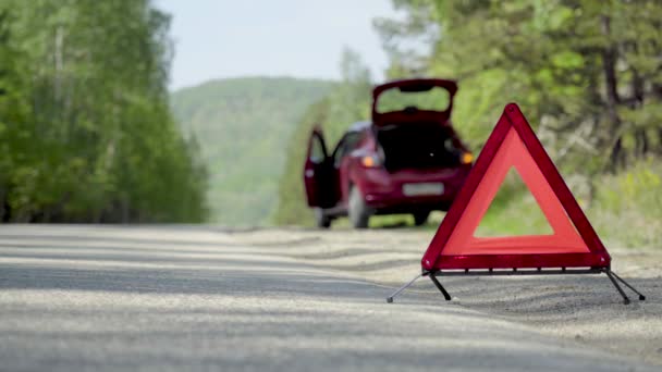 Знак аварійної зупинки на лісовій магістралі перед зламаним автомобілем — стокове відео