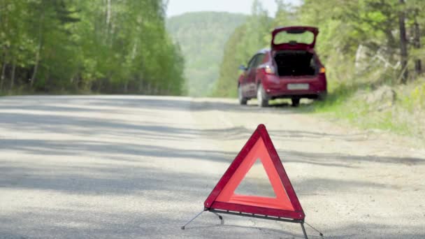 Vészleállító tábla egy erdei autópályán egy törött autó előtt. — Stock videók