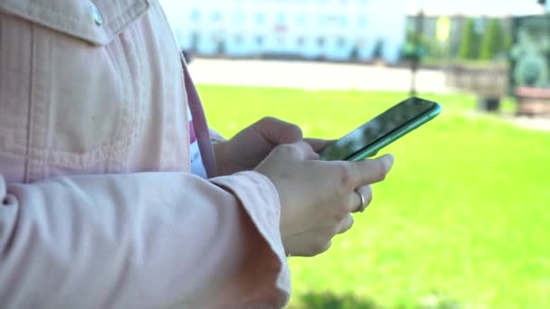 Κοντινό πλάνο. Χρησιμοποίησε ένα smartphone στο πάρκο. Γυναίκα χρήση του κινητού τηλεφώνου στο πάρκο της πόλης — Αρχείο Βίντεο