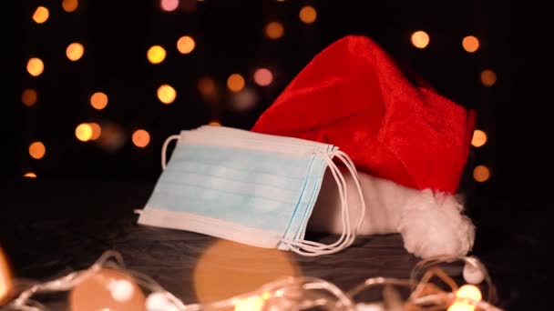 Red Papai Noel Cap e máscaras médicas no fundo das luzes de Natal — Vídeo de Stock