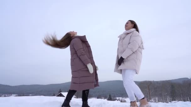 Deux filles profitent de la vie et de la neige propre. Loisirs actifs dans la nature par une journée d'hiver enneigée — Video