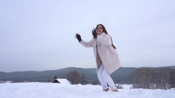 En ung flicka njuter av livet och ren snö. Aktiv rekreation i naturen en snöig vinterdag — Stockvideo