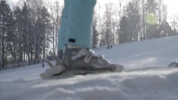 Pista da sci sullo sfondo della foresta. Le gambe di uno sciatore che sale in ascensore. Scarponi da sci Primo piano — Video Stock