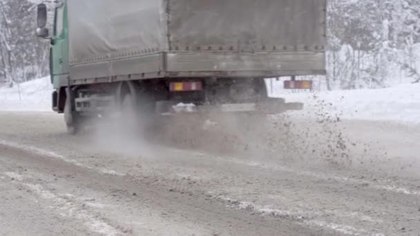 Nieve suelta vuela desde debajo de ruedas de camiones en la carretera — Vídeos de Stock