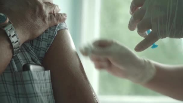 Uma médica fêmea vacina um homem idoso contra o coronavírus. — Vídeo de Stock
