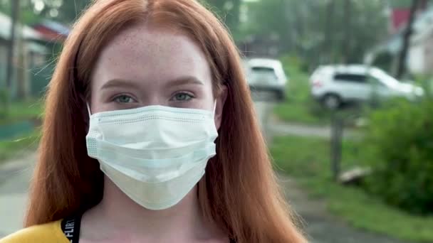 Menina ruiva em uma máscara médica em uma rua de verão — Vídeo de Stock