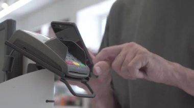 Ödeme sırasında Pos terminaline yakın çekim. Hesabın parasını ödemek için akıllı bir telefonla kablosuz bağlantı.