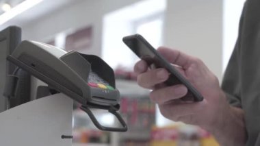 Ödeme sırasında Pos terminaline yakın çekim. Hesabın parasını ödemek için akıllı bir telefonla kablosuz bağlantı.