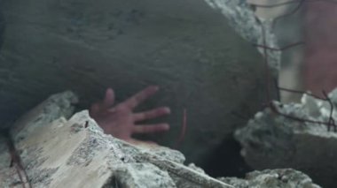 Evi yıkan bir adamın eli. Deprem veya patlama sırasında güçlendirilmiş beton levha ile bastırılmış.