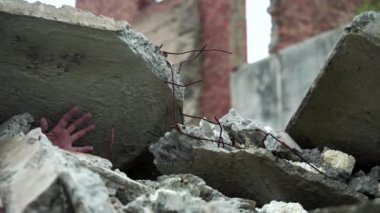 Evi yıkan bir adamın eli. Deprem veya patlama sırasında güçlendirilmiş beton levha ile bastırılmış.