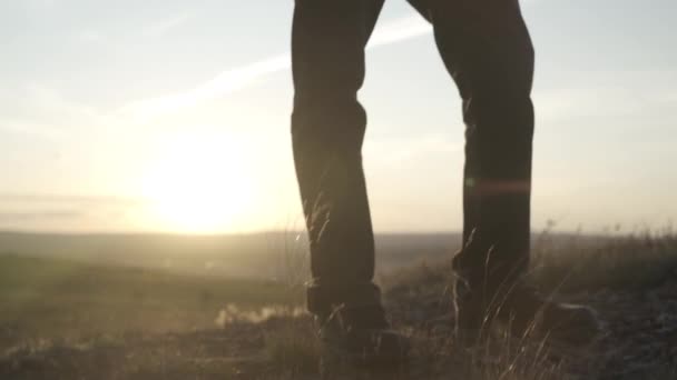 Bir gezginin bacakları gün batımının arka planında tepenin üzerinde duruyor. — Stok video