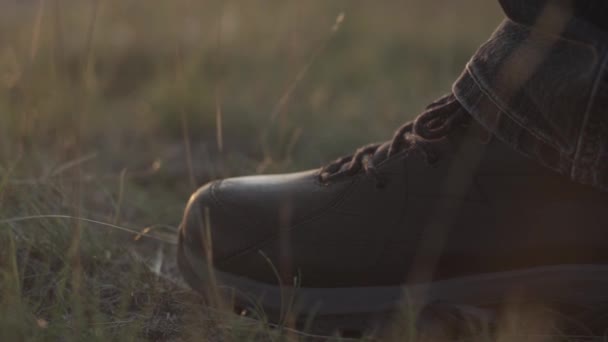 La bota de un viajero que se detiene en una colina sobre el telón de fondo de una puesta de sol — Vídeo de stock