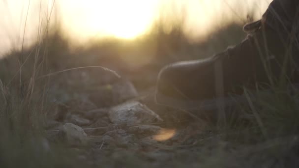 在日落的背景下停留在山上的旅行者的靴子 — 图库视频影像
