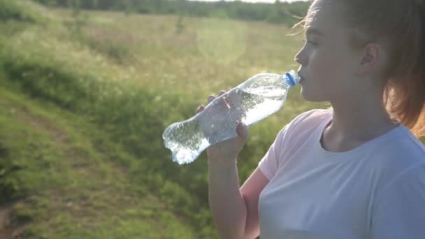 Девушка открывает бутылку минеральной воды и напитки, наслаждаясь — стоковое видео