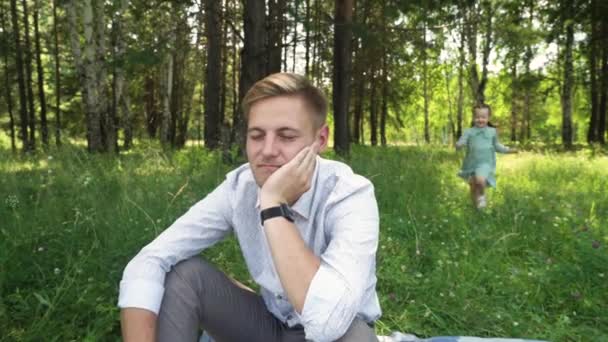 5-jähriges Mädchen lässt ihren Vater nicht traurig sein. Vater und kleine Tochter spielen im Sommerpark — Stockvideo