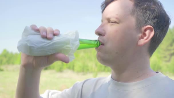 Lábios masculinos e pescoço de uma garrafa de cerveja close-up. Jovem gordo bebe cerveja de uma garrafa de vidro verde — Vídeo de Stock