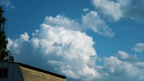 Weiße Wolken wirbeln auf. Zeitraffer. Weiße Kumuluswolken ziehen rasch über das Schieferdach eines Hauses — Stockvideo