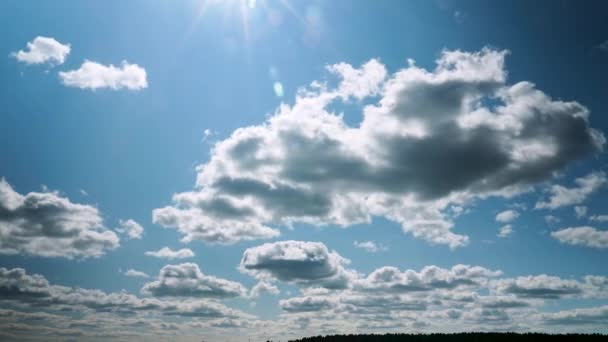 Ruch wielu chmur. Słońce świeci na obiektyw. Timelapse pięknego słonecznego błękitnego nieba z białymi puszystymi chmurami — Wideo stockowe