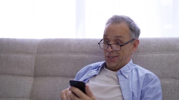 Pensionista se regocija en ganar mientras mira la pantalla del teléfono inteligente — Vídeos de Stock