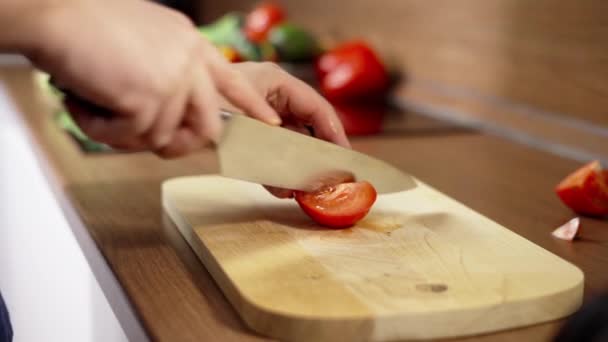 Mužské ruce s kuchyňským nožem krájely čerstvé rajče na dřevěné řezací desce. Zdravé stravování — Stock video