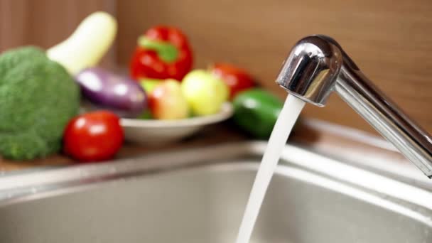 A stream of water from the tap on the background of vegetables. Close-up — Stock Video