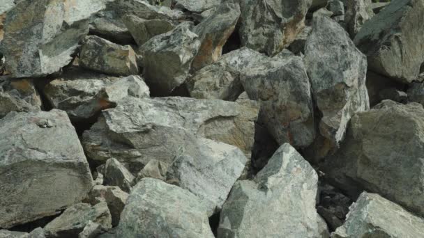 Une pile de débris de pierre tranchants. Un tas de grosses pierres naturelles. Des pierres gris clair gisent sur une colline de montagne en plein jour close-up — Video