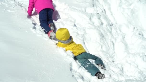 I bambini si arrampicano e scivolano sulla neve pura in una giornata invernale soleggiata — Video Stock