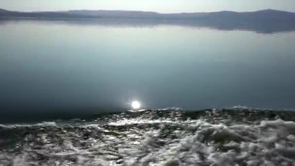 Хвилі на дзеркальній поверхні з моторного човна на спокійному лісовому озері. Розслабляючий природний ландшафт, екотуризм — стокове відео