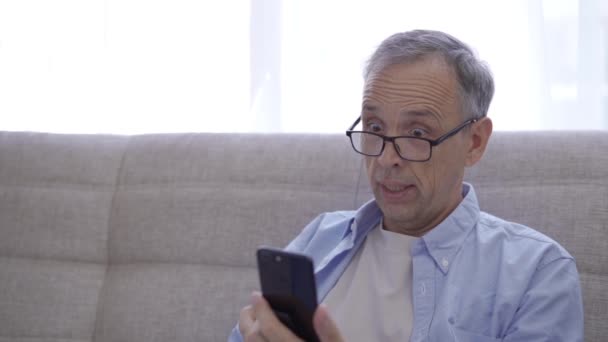 Důchodce se raduje z vítězství při pohledu na obrazovce smartphone — Stock video
