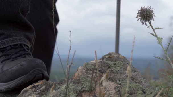 Los pies de los turistas en zapatos pisan la roca. Bota en el fondo de una cordillera. Protección de las piernas contra daños — Vídeo de stock