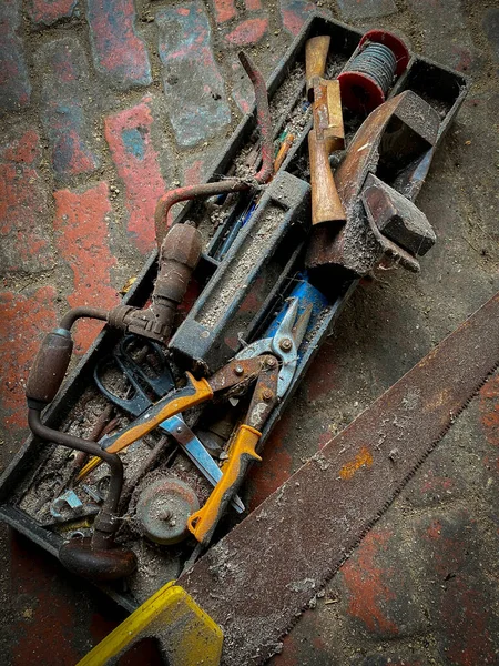 Old tools on the floor a shed with muck and cobwebs.