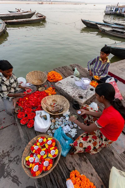 インド北部のヴァラナシにある聖なる川のほとりにあるヒンズー教の帽子を宗教的に提供する子供たち — ストック写真