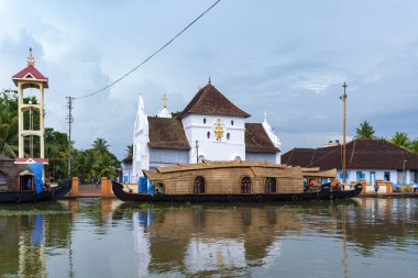 Hindistan 'ın güneyindeki Kochi yakınlarında Kerala Sahili' nin iç sularındaki Hristiyan Kilisesi yakınlarında demirlemiş turist pirinç mavnası (yüzen ev)..