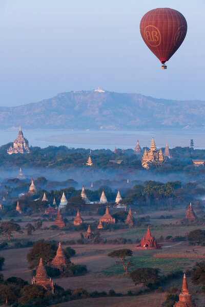 An early morning aerial view of a hot air balloon and a few of the hundreds of temples in the Archaeological Zone of the ancient city of Bagan in Myanmar (Burma).