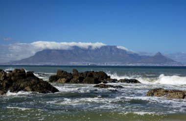Güney Afrika Bloubergstrand 'dan görünen Masa Dağı ve Cape Town manzarası. Dağın üzerindeki bulutlara masa örtüsü denir..                             