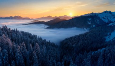 Güneşin doğuşunda vadide, dağların tepesinde, sisli ve alçak bulut.