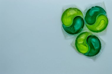 Beyaz arkaplan kopyalama alanı üzerinde yeşil ve sarı jel ile yıkama kapsülleri