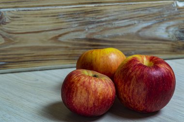 Tahta arka planda üç kırmızı elma. Yakın plan.