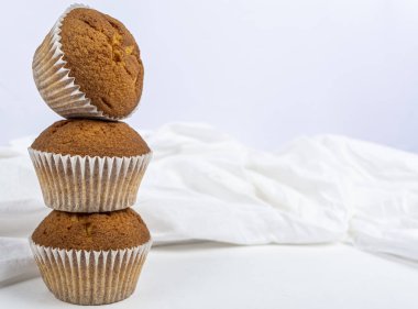 Beyaz arka planda üç kek ve beyaz kumaş.